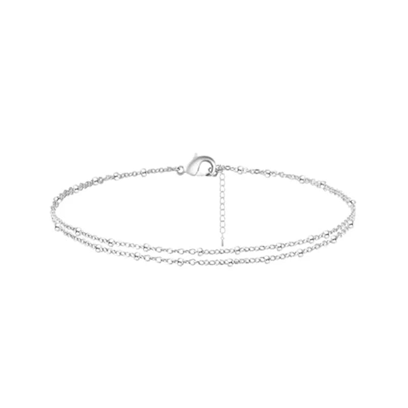 Layered gold and silver plated anklets displayed flat