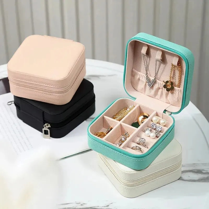A light pink and mint green compact leather jewelry travel organizer with multiple compartments.