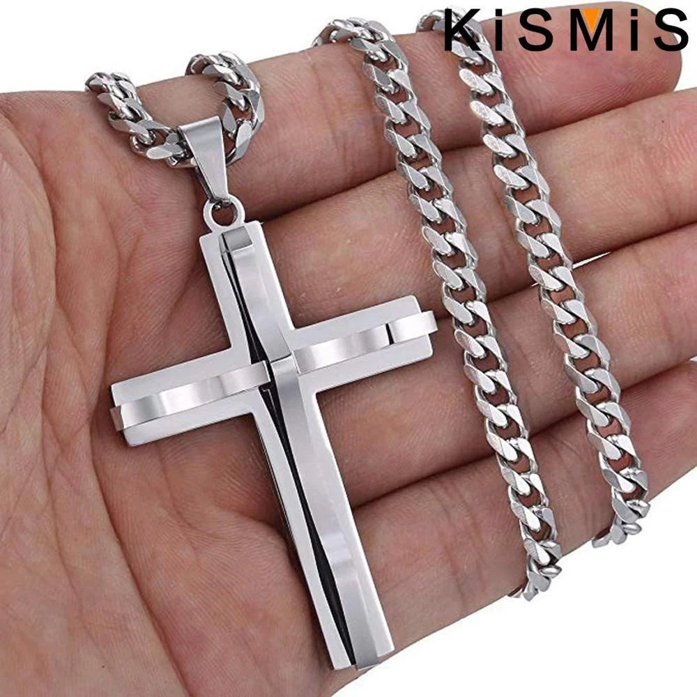 Un colgante y cadena de cruz de acero inoxidable mostrados en la mano de una persona.