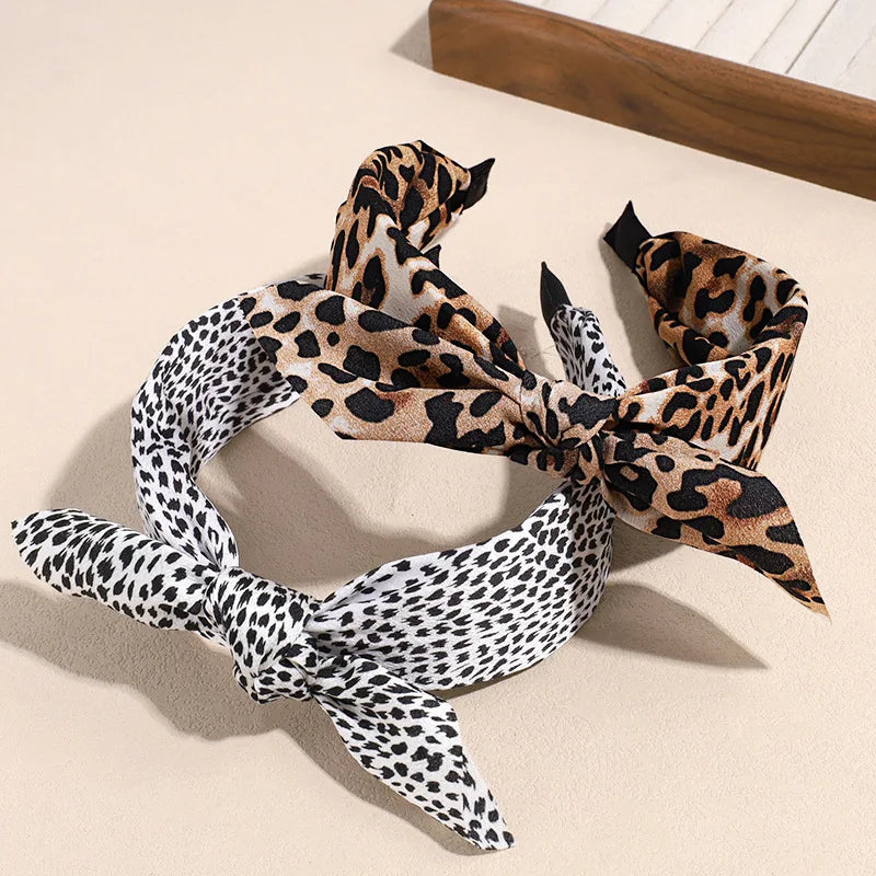 A leopard print retro bow hairband tied in a decorative knot, lying on a light surface.