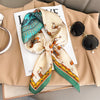 A beige blazer displays a silk scarf featuring an orange and green pattern, laid out on a white card.