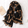 Luxuriöses Pashmina-Schal mit schwarz-beige Streifen, drapiert auf weißem Untergrund.