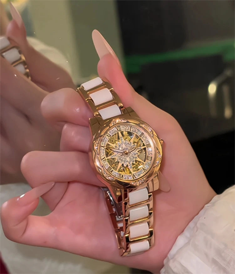 Una mano sostiene un elegante reloj de cuarzo con diamante dorado y correa blanca.
