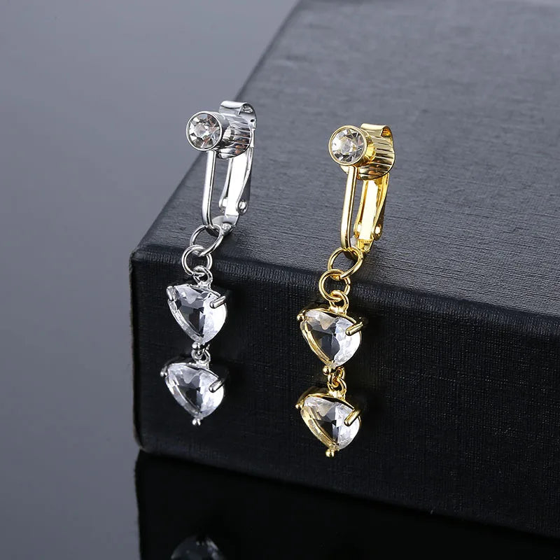 A pair of gold-toned fashion belly button rings with clear and gold-colored stones displayed on a black box.