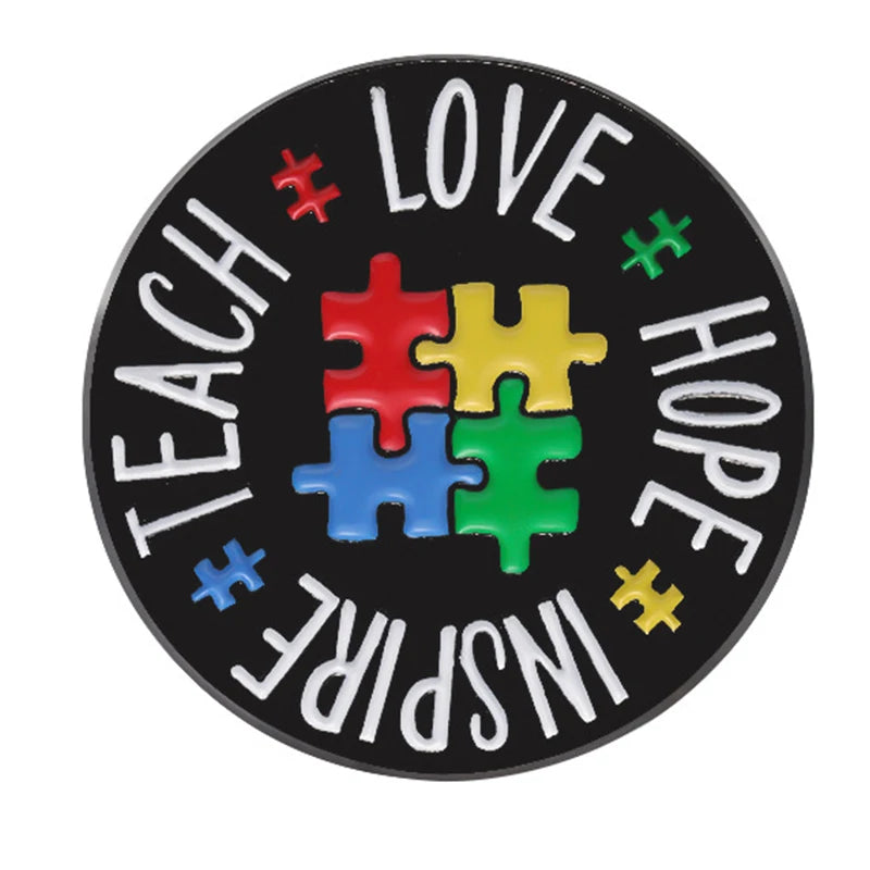 An enamel lapel pin featuring the words TEACH LOVE INSPIRE HOPE formed by colorful puzzle pieces.