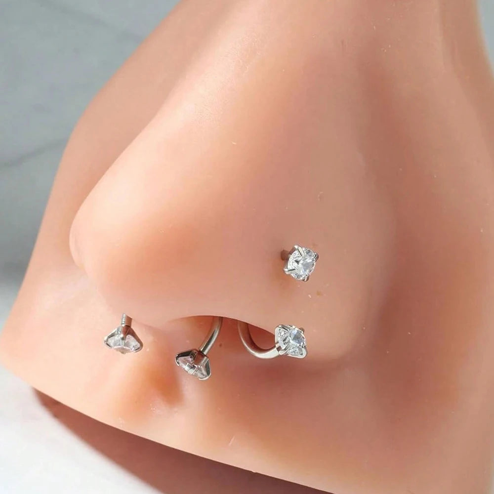 Tres aretes de concha de acero inoxidable mostrados en la naricita de un modelo de tono de piel.