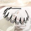 A black rhinestone butterfly hair accessory is displayed on a white surface next to a white cup.
