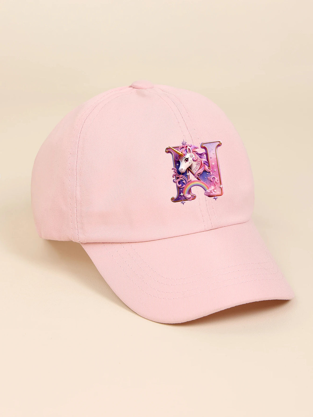 A pink baseball cap featuring a purple unicorn letter design.