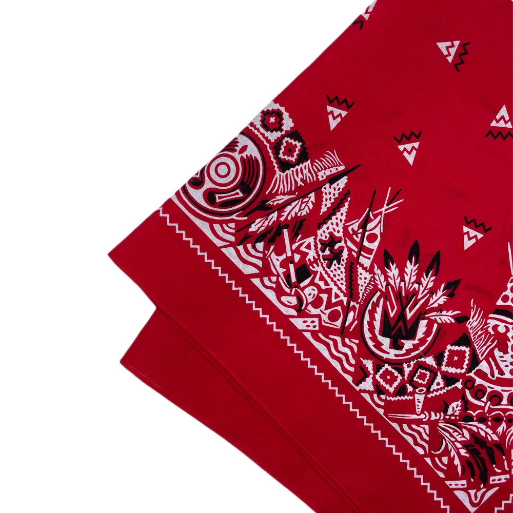 A close-up of a red bandana scarf featuring intricate white and black geometric patterns.