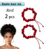 A pair of red satin hair ties or scrunchies shown next to a woman with curly hair.