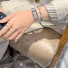 A close-up of a woman's hand wearing a vintage gold stainless steel quartz watch and rings, resting on a light fabric.