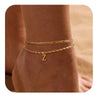 Primer plano de una pulsera y un tobillera de adorno dorado en la muñeca de una persona.