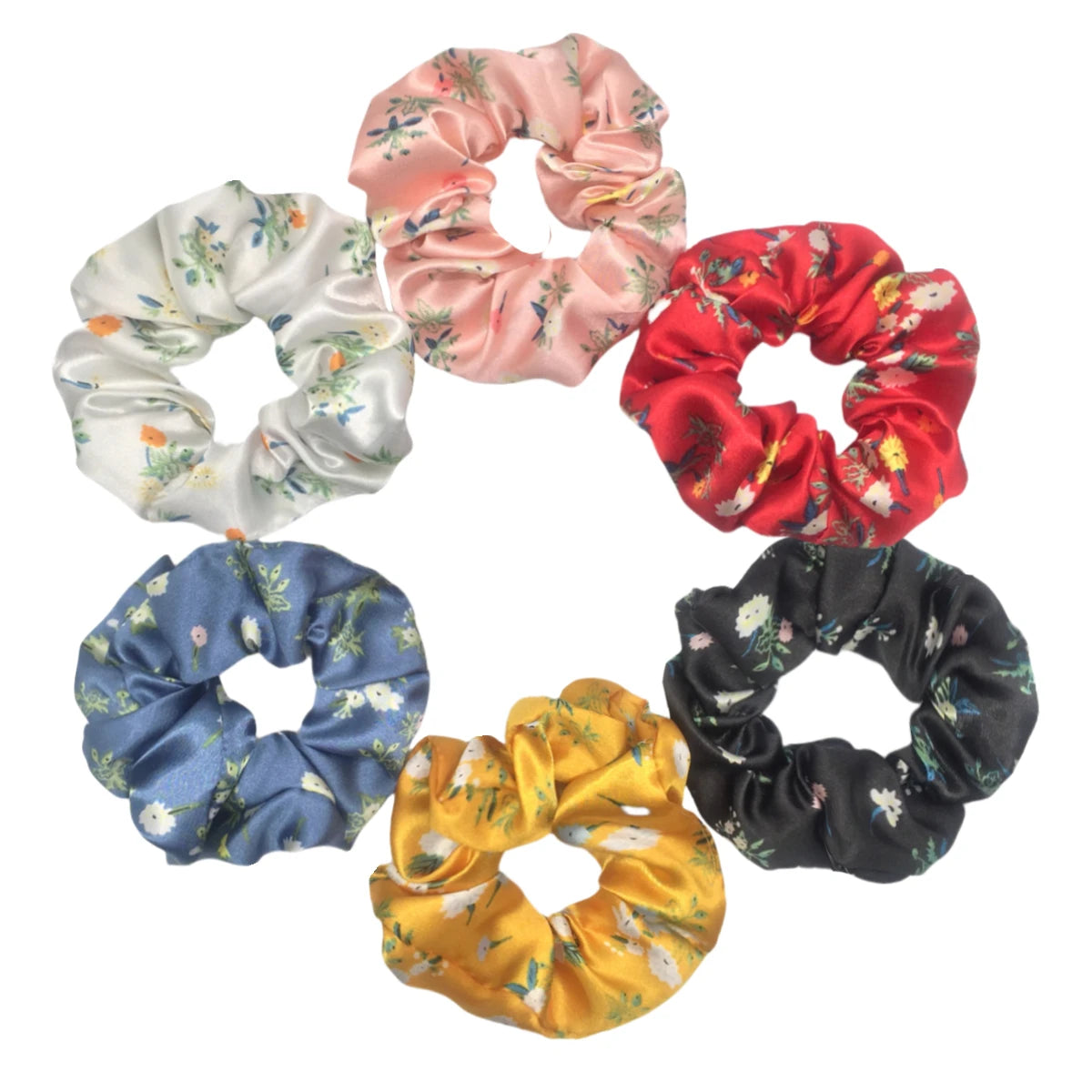 Un set de seis gomas para el pelo con estampado floral de satén en rosa, rojo, blanco, azul, amarillo y negro.