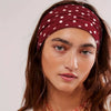 A close-up of a woman wearing a maroon polka dot stretch headband on her dark hair.