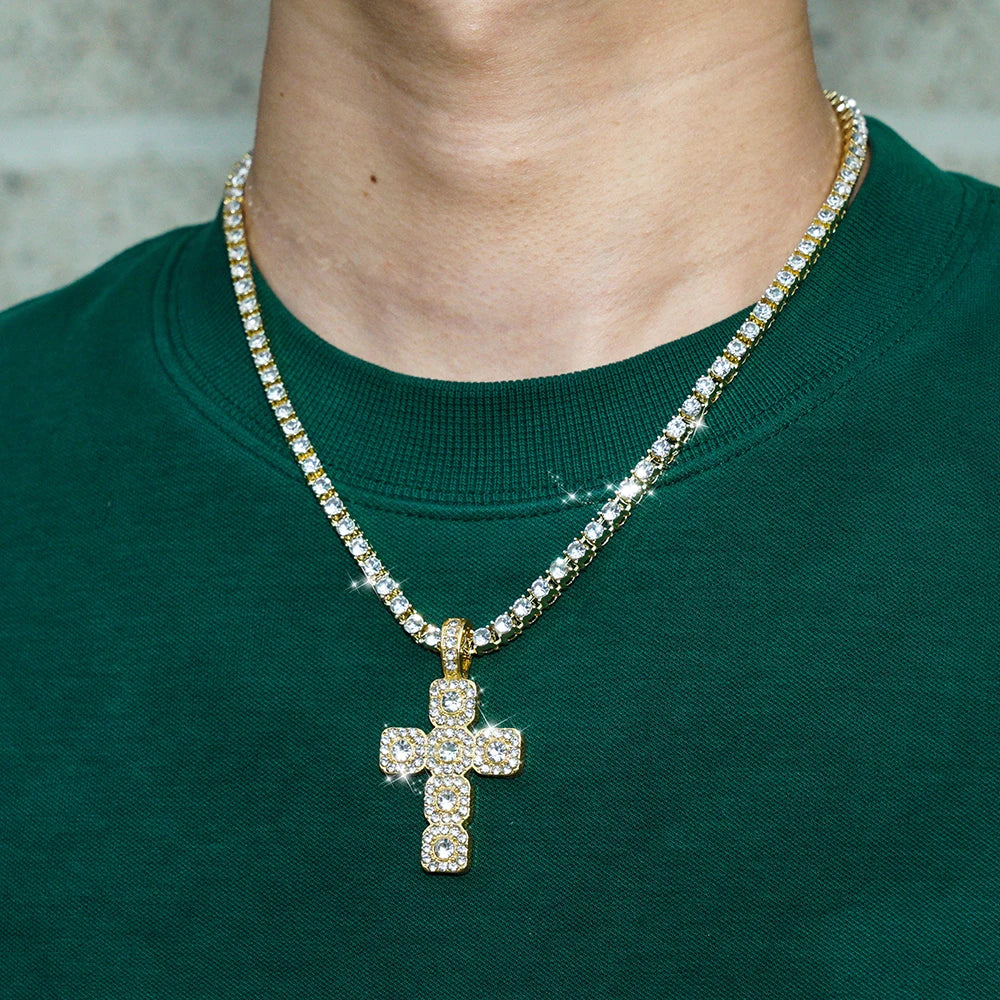 A sparkling rhinestone cross pendant necklace worn around the neck against a dark green sweater.