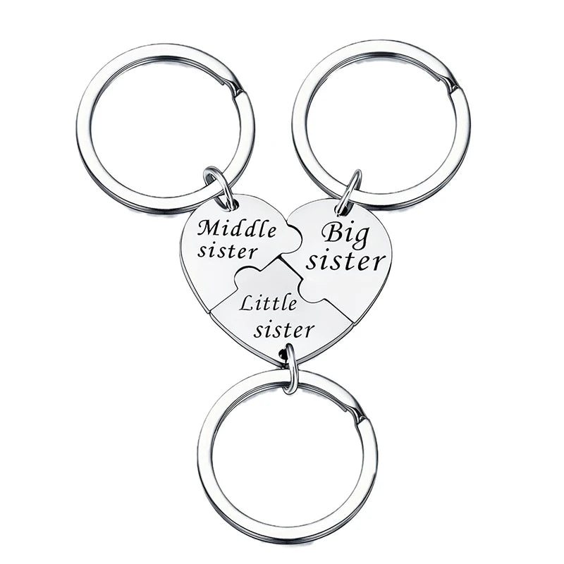 A silver keychain set featuring three puzzle heart charms labeled Middle sister, Big sister, and Little sister.