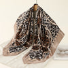 A square satin scarf featuring a leopard print design in shades of brown and black.