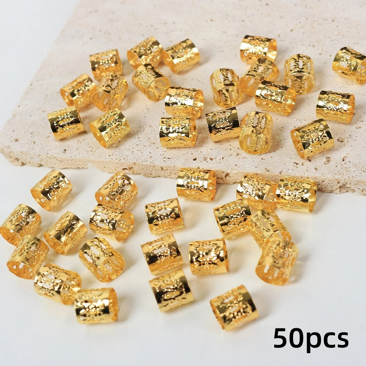 Un juego de 50 anillos y clips de cabello metálicos texturizados de color dorado esparcidos sobre una superficie clara.
