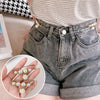 A pair of gray denim shorts is shown alongside a hand displaying heavy duty pearl safety pins for clothing.