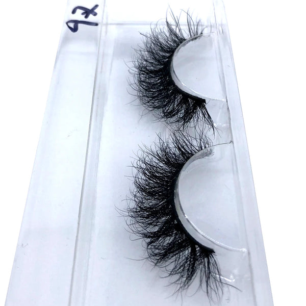 A pair of natural mink false eyelashes displayed on a clear plastic slide.