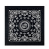 Black fabric featuring intricate white paisley and floral patterns on a square bandana scarf