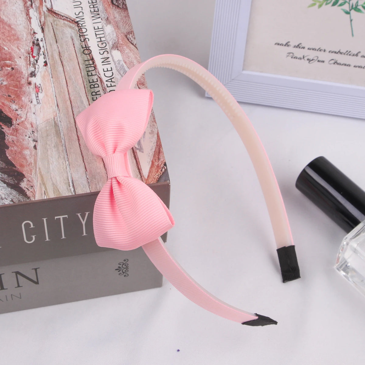 Pink grosgrain ribbon hair bow with black tips displayed on a white surface.