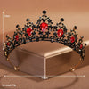 A gold-toned crystal baroque bridal tiara headpiece with red stones displayed on a box.