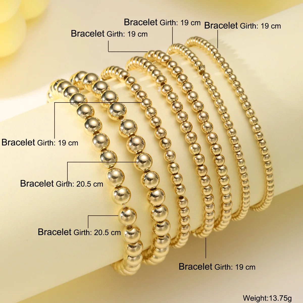 A set of gold-toned beaded bracelets with various girths shown on a white background.