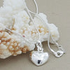 A silver heart-shaped necklace featuring a snake charm, displayed against a background of white coral.
