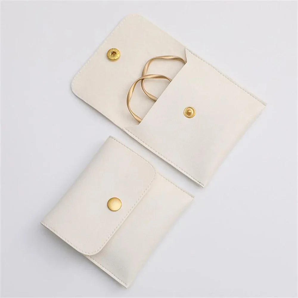 A light beige PU leather jewelry pouch with a flap secured by a gold-toned snap button and a gold chain.