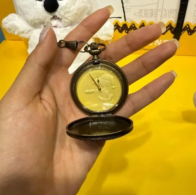Eine Hand hält eine goldfarbene, vintage-Stil-Taschenuhr mit offenem Gehäuse und Kette vor gelbem Hintergrund