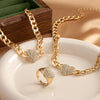 Gold chain necklaces and a ring featuring rhinestone heart charms displayed on a white plate.