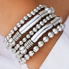 A set of silver and gold-toned beaded bracelets stacked on a person's wrist.