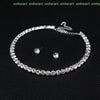 A silver-toned necklace and matching earrings set with clear crystals displayed on a black background.
