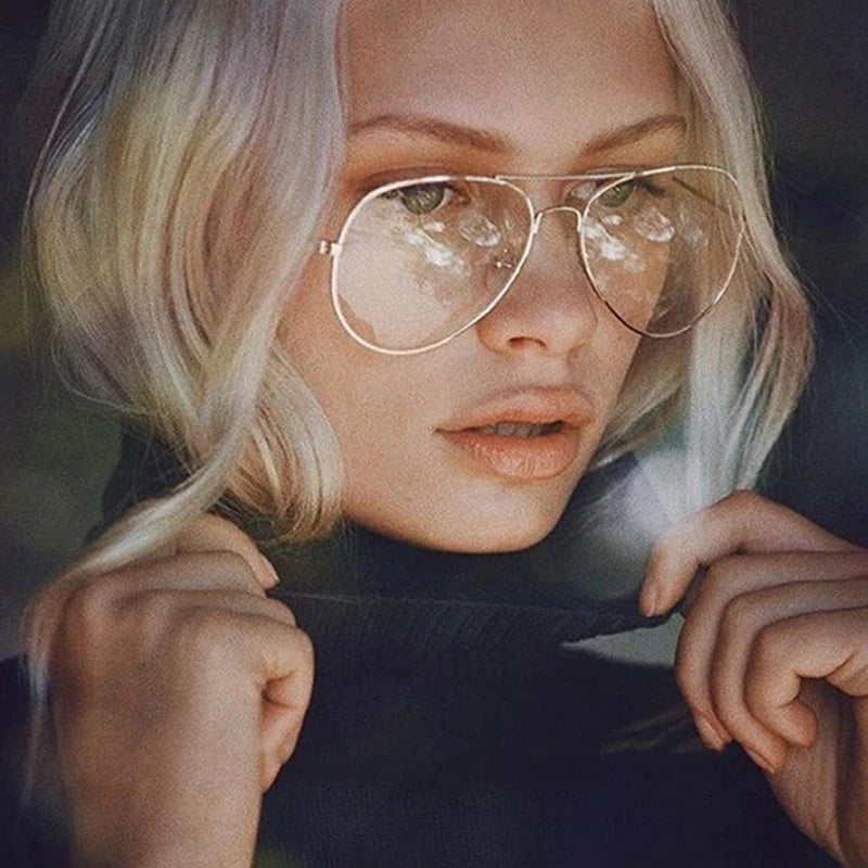Gros plan d'une femme portant des lunettes à monture dorée rétro avec une lentille givrée.