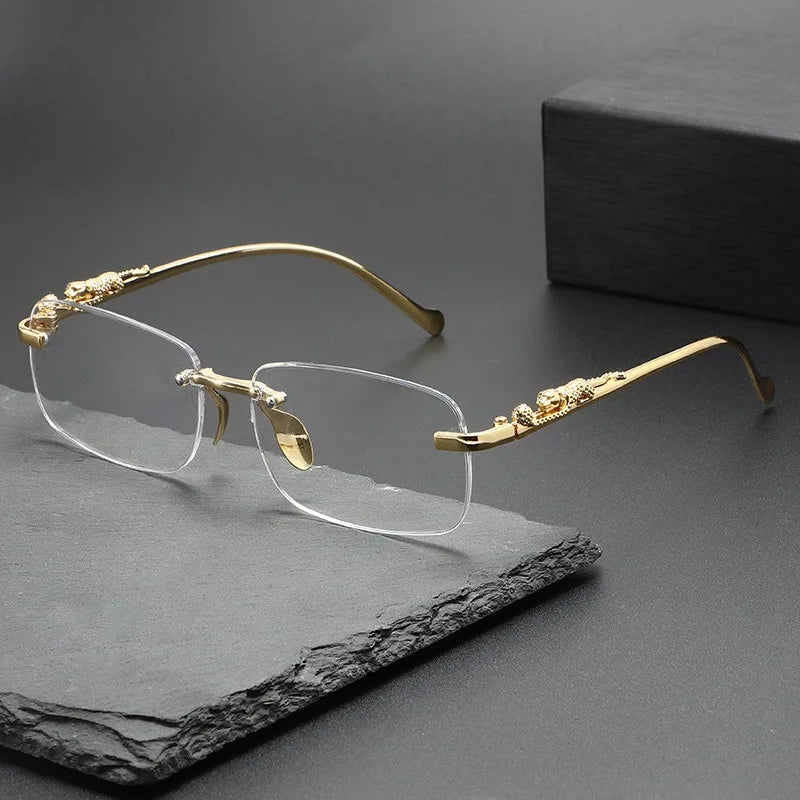 Gold-rimmed rimless square sunglasses resting on a dark slate surface.