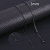 A set of black stainless steel Cuban link necklaces displayed on a dark leather surface.
