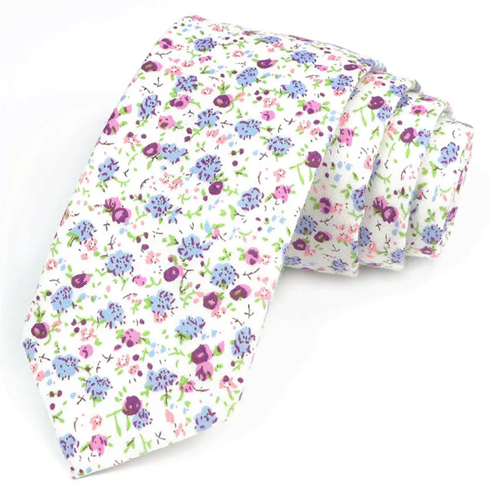 Une pile de nœuds papillons en coton à imprimés floraux élégants, avec des fleurs violettes, roses et bleues sur fond blanc.
