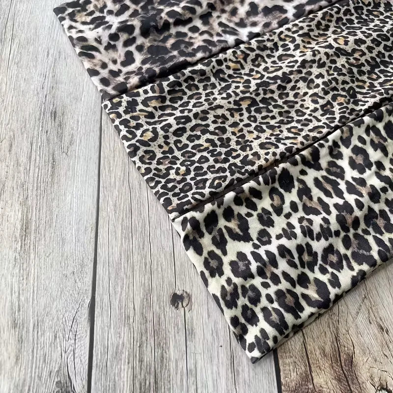 Diadema deportiva impermeable de estampado leopardo negro y marrón, doblada sobre una superficie de madera.