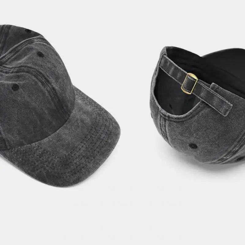 A dark gray washed cotton snapback cap with a black mesh back and a gold-toned strap detail.
