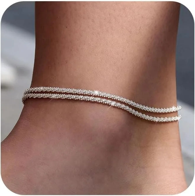 Silver plated beaded anklets worn around the ankle of a person.