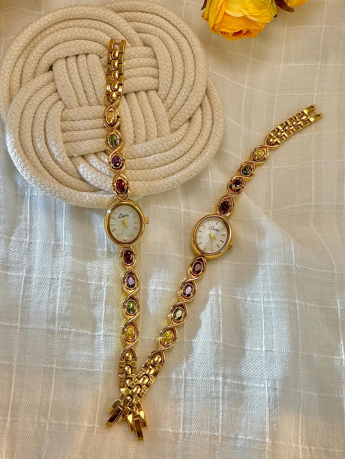 Goldfaruener modischer Armband mit Turmalin- und Strassakzenten, neben einem gewebten beigen Objekt.