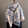 A patterned scarf and shawl wrap in blue, beige, and pink tones displayed on a wooden hanger.