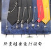 A set of silver chain necklaces displayed against a backdrop of various colored neckties.