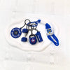 A collection of blue fitness keychains and weightlifting accessories including a dumbbell and a lifting tool displayed on a w