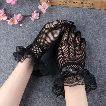 Black sheer lace fishnet evening gloves worn on a hand and arm against a gray background.