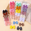 Assortment of handmade ribbon bow hair clips in various shades of pink, purple, yellow, and beige.