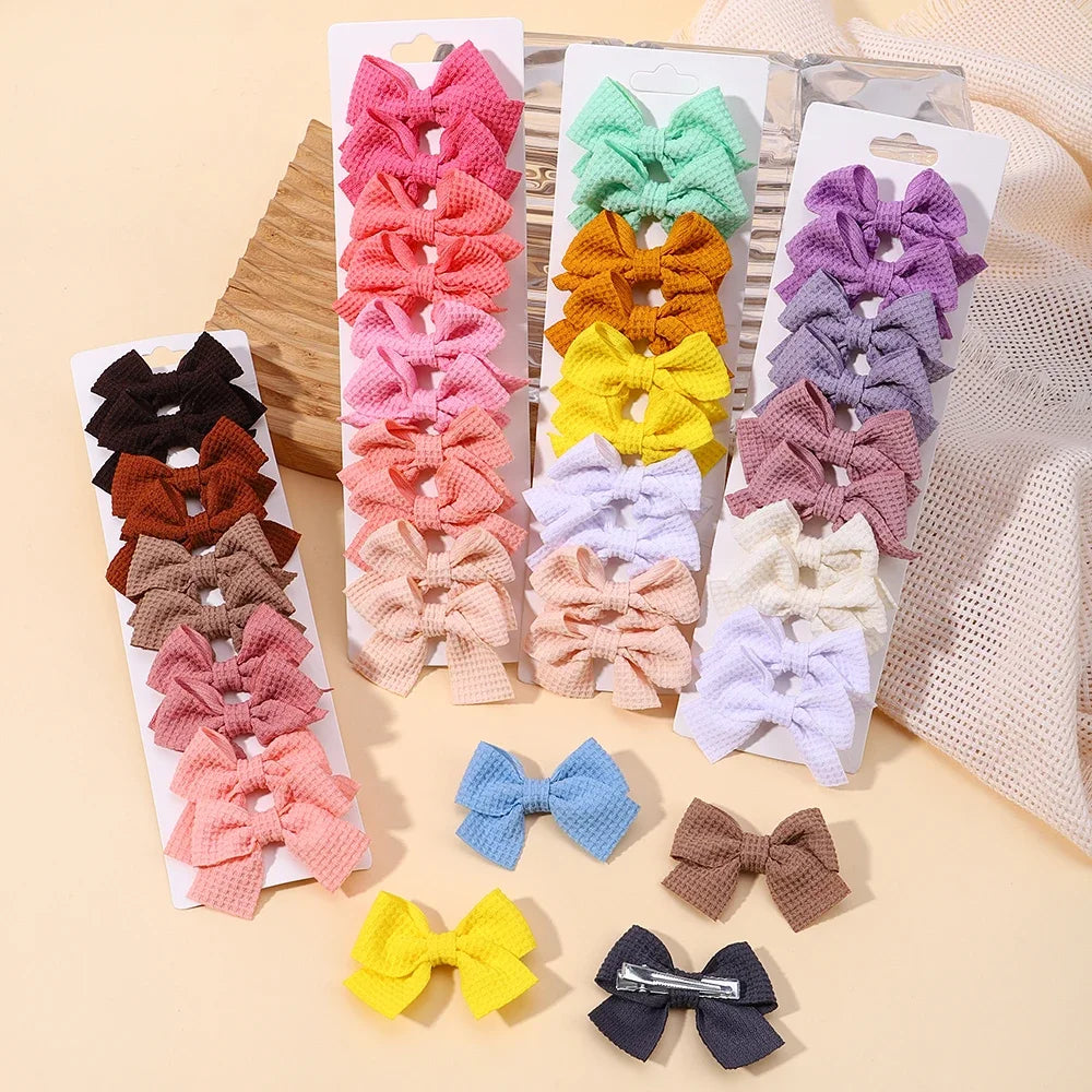 Assortment of handmade ribbon bow hair clips in various shades of pink, purple, yellow, and beige.