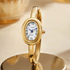 A gold ZIDO quartz analog watch with an oval face displayed on a reflective surface.