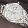 A silver-toned luxury quartz wristwatch with a white dial and date display, shown from above.
